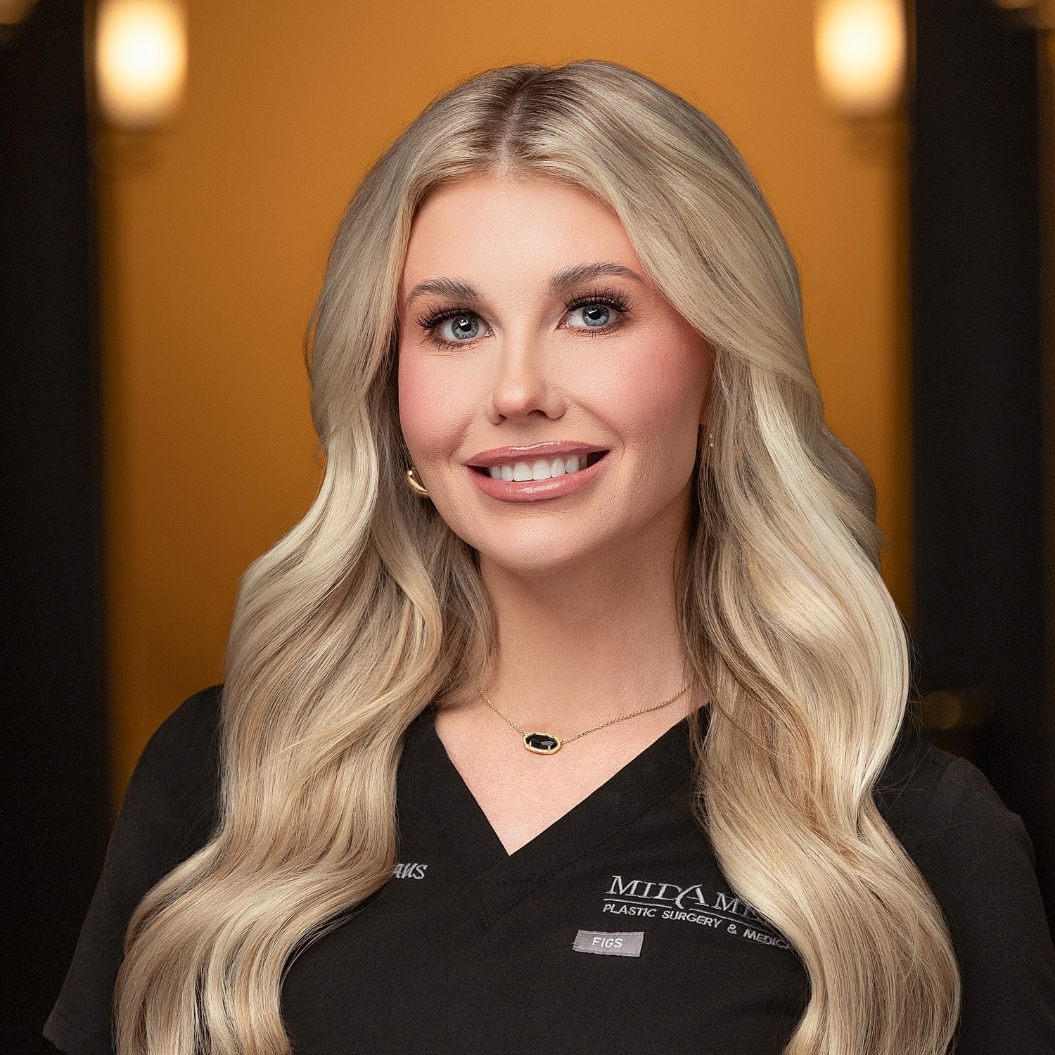 Blonde professional in medical scrubs smiling warmly.