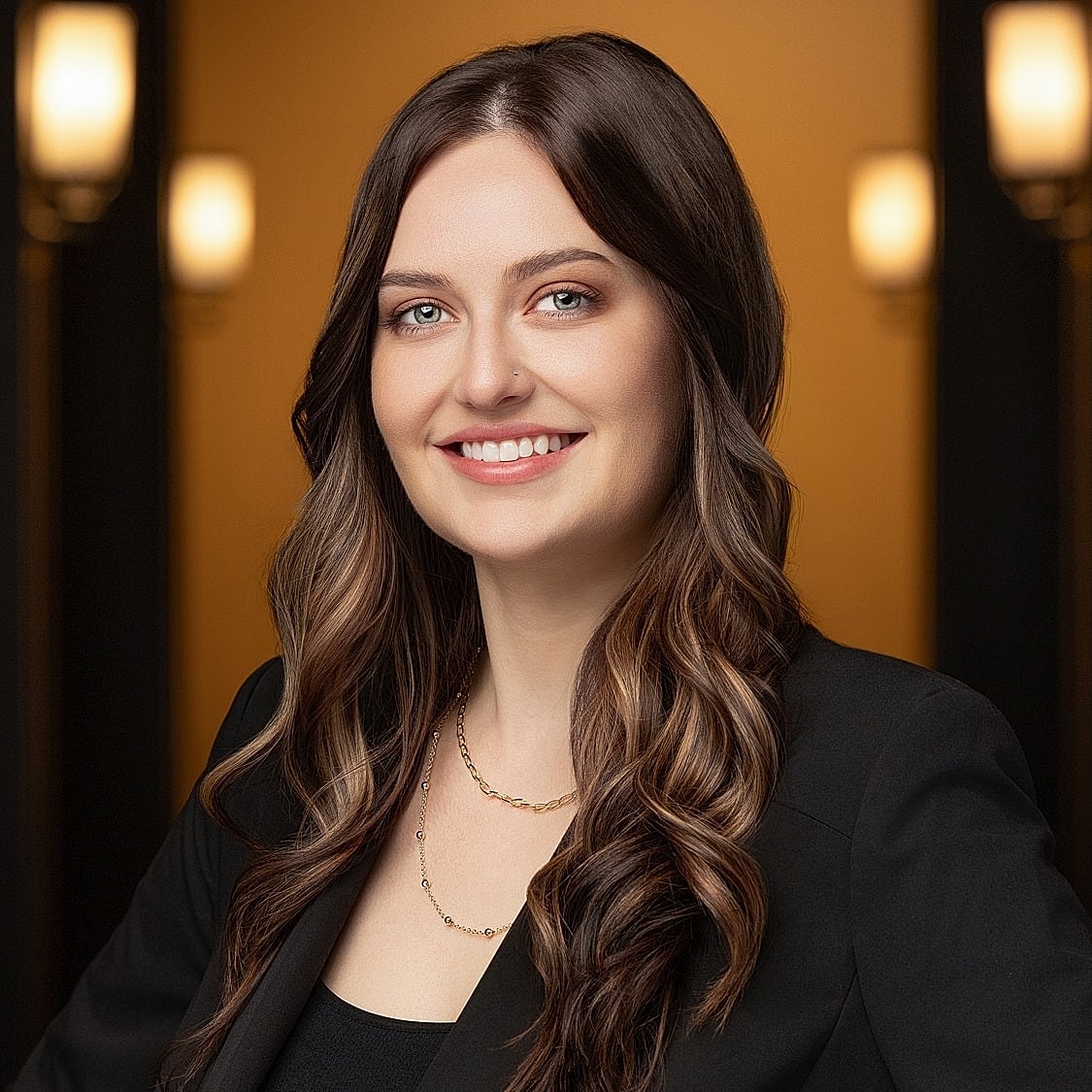 Smiling woman in professional attire against warm background.