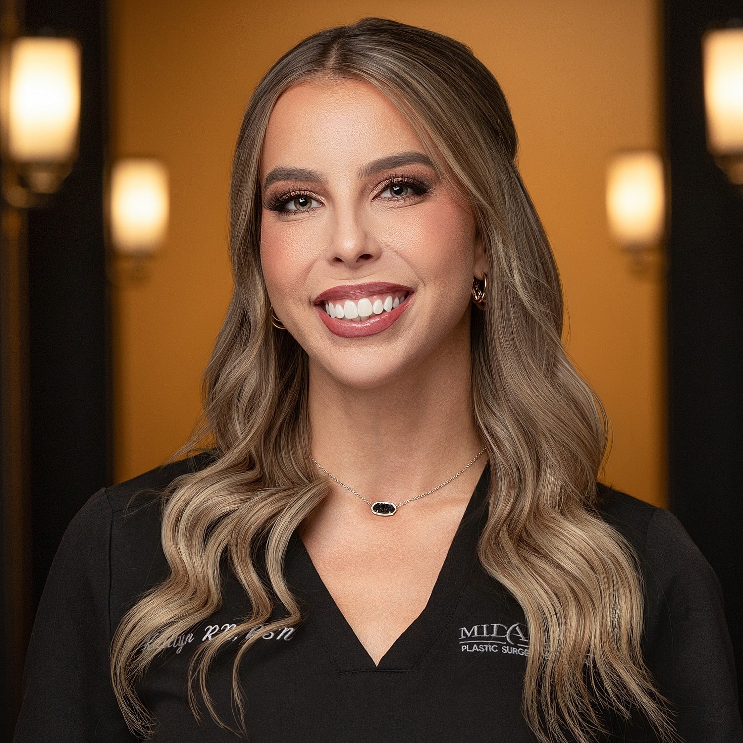 Smiling woman in medical attire, professional setting.