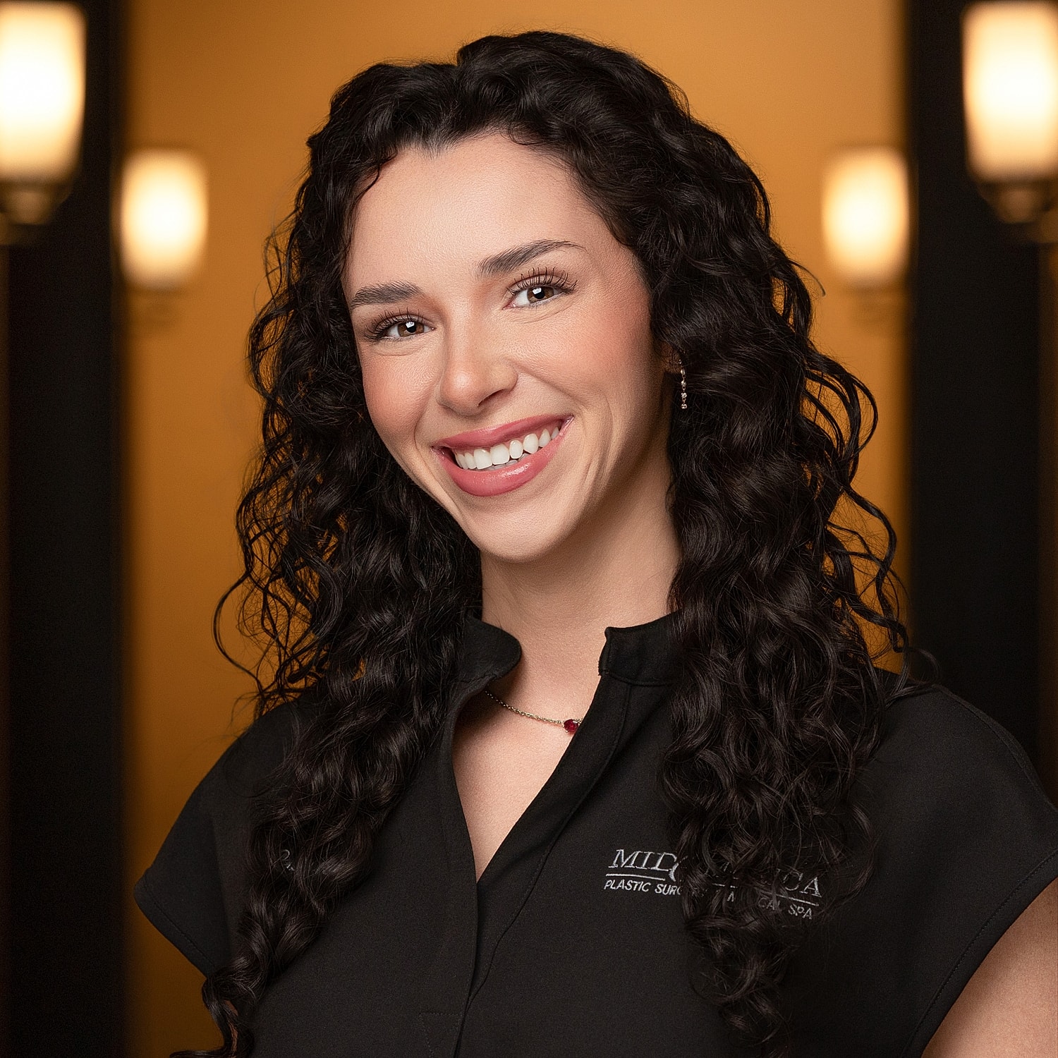 Smiling woman with curly hair in black attire.